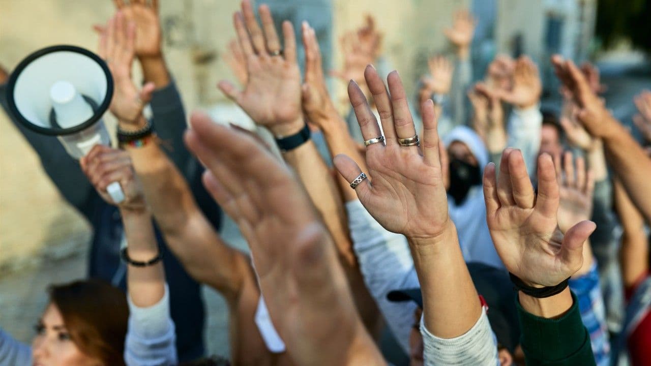 photologuephotos2025-03closeup-crowd-protesters-with-arms-raised-demonstrating-streets_1jpg