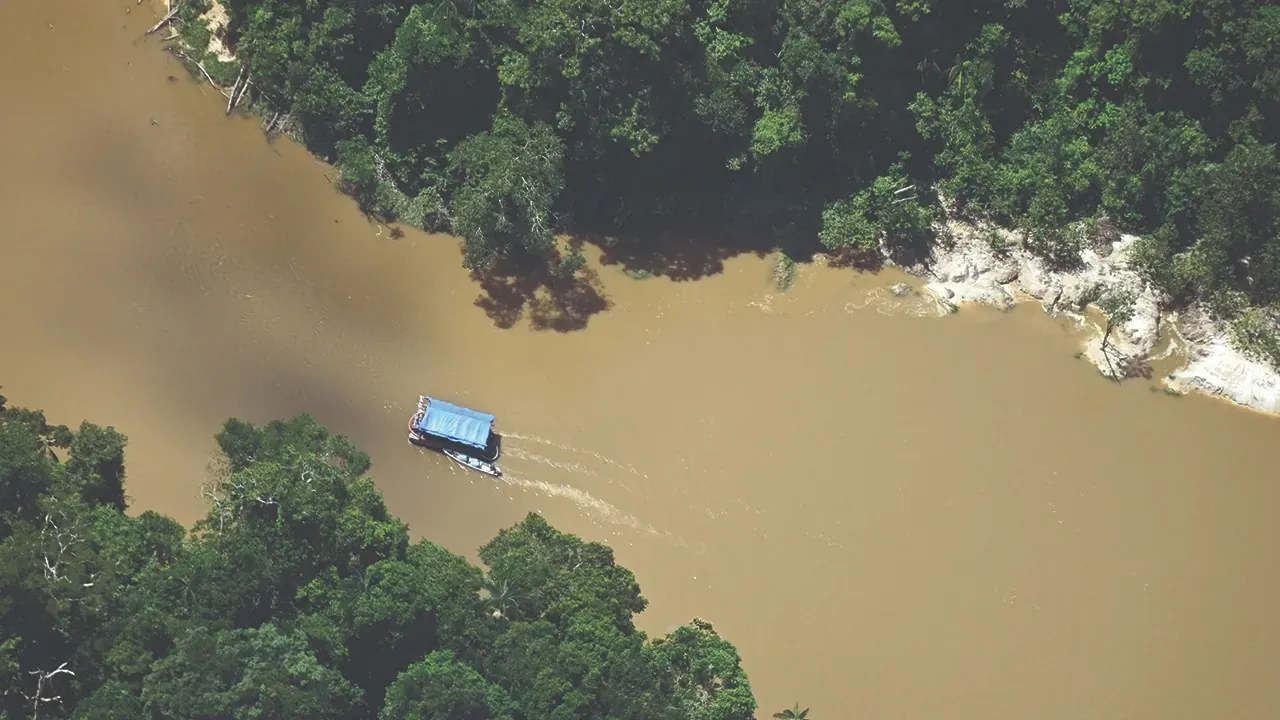 Embarcación sobre un río de aguas turbias en la Amazonía.