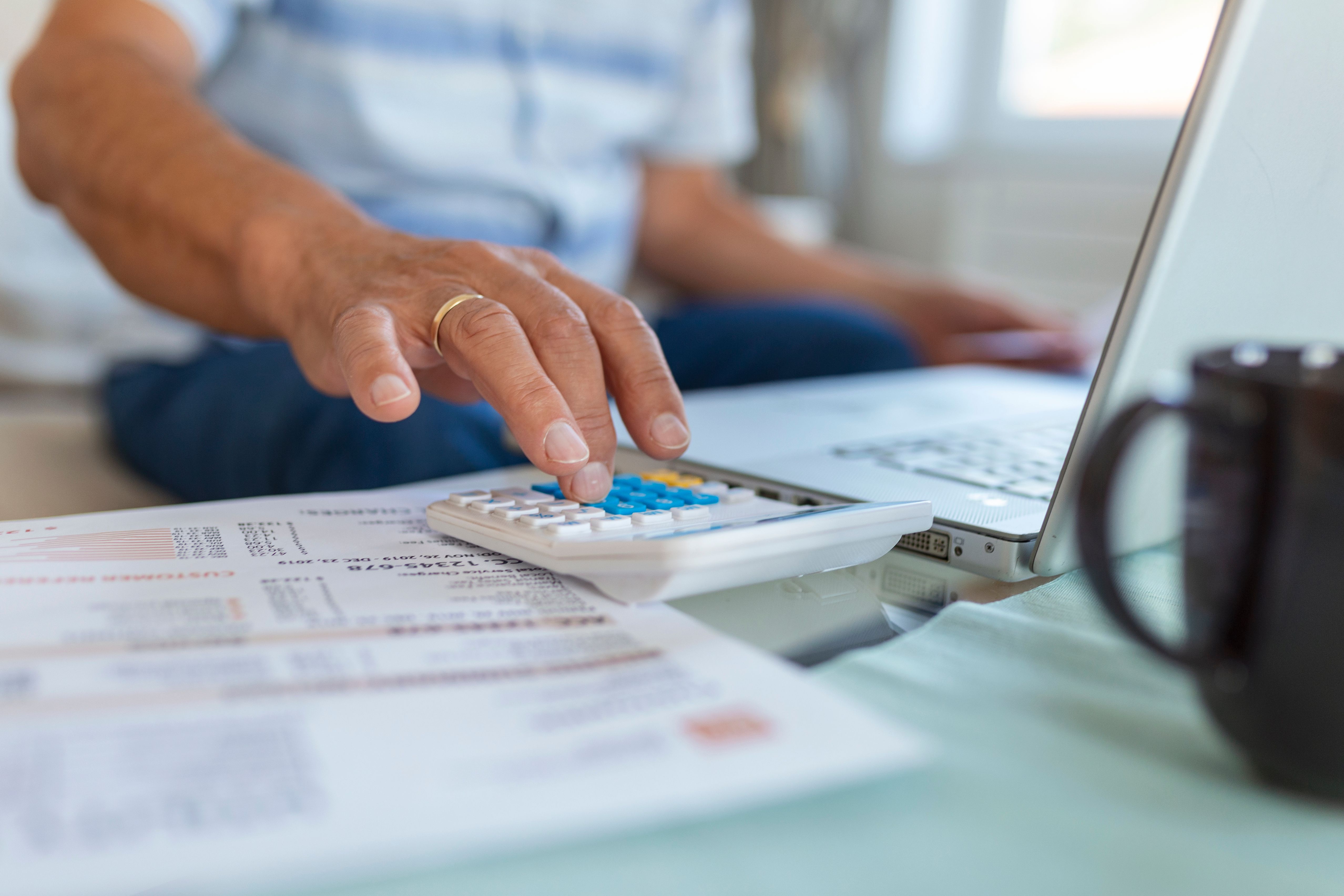 serious-elder-senior-greyhaired-grandpa-using-calculator-counting-bank-loan-payment-holding-papers-home-focused-mature-old-man-doing-paperwork-calculating-bills-managing-finances-sit-sofa.jpg