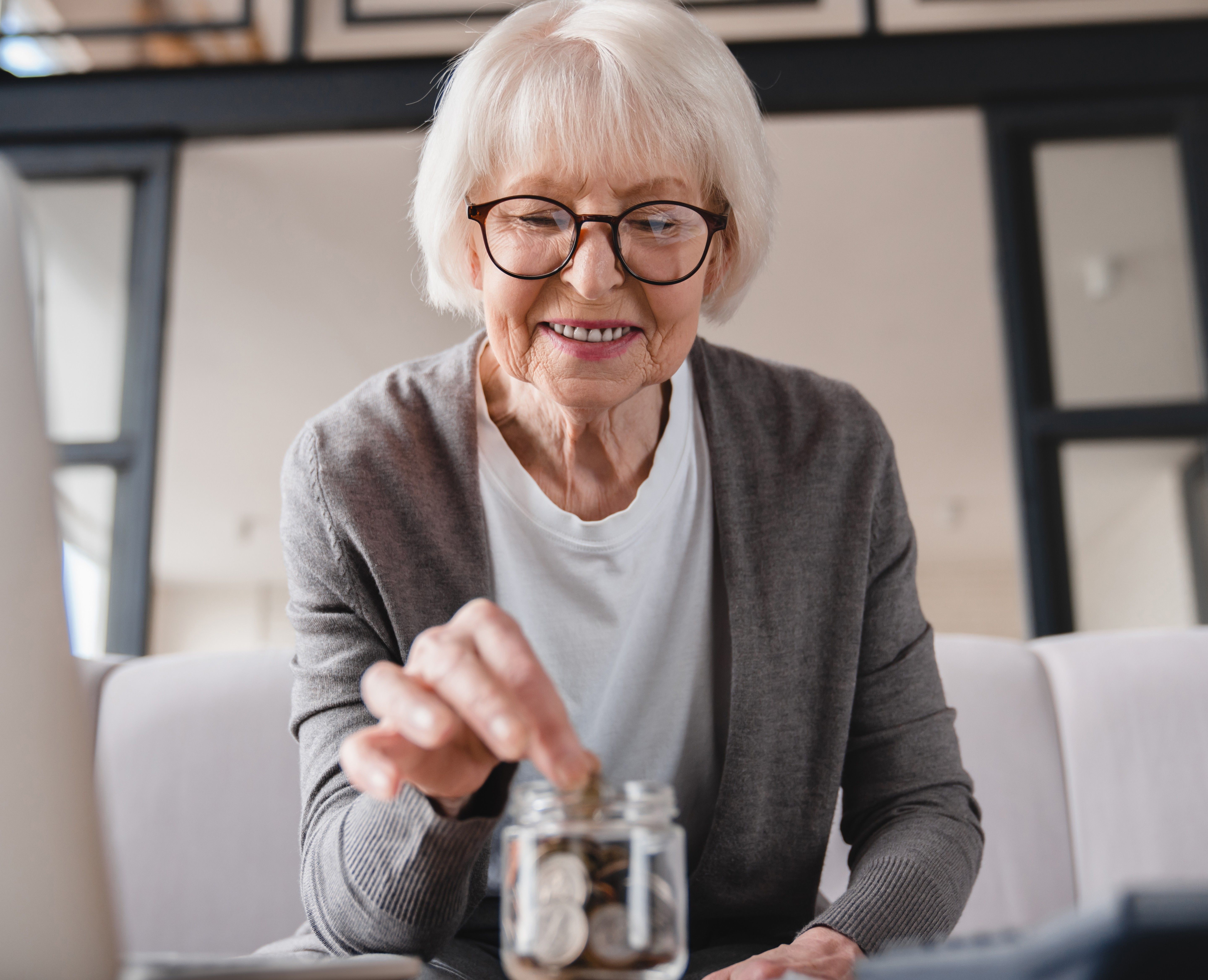 concepto-de-ahorro-huevo-de-nido-de-anciana-anciana-abuela-ahorrando-dinero-ahorrando-pensiones-prestamo-hipotecario-en-casa-usando-portatil-y-poniendo-monedas-en-la-caja-de-dinero.jpg