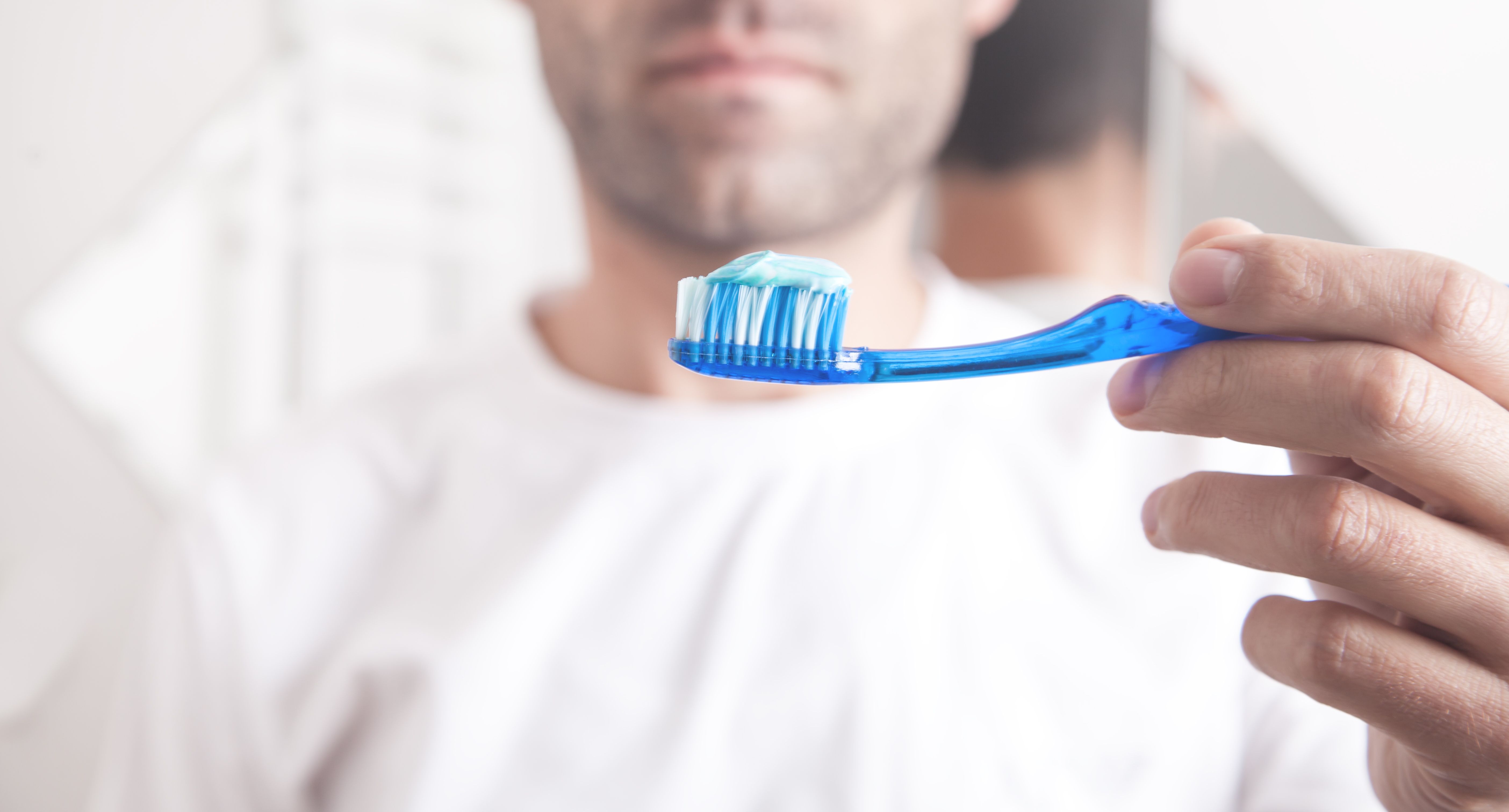 hombre-sujetando-pasta-de-dientes-azul-y-cepillo-de-dientes.jpg