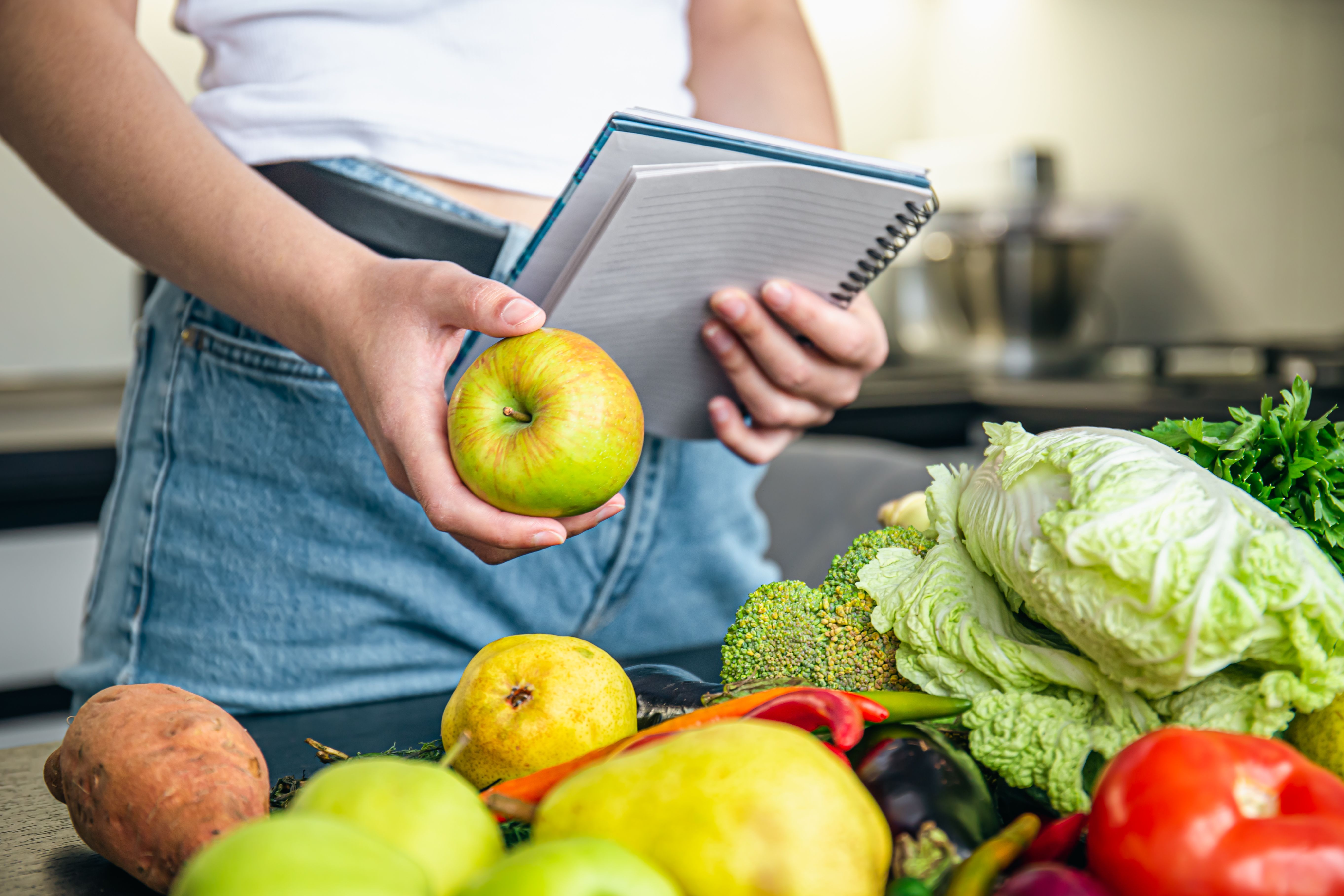 woman-with-notepad-vegetables-kitchen-table-preparing-recipe.jpg